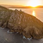 Il faro di Capo Finisterre domina le scogliere della Costa da Morte al tramonto, dove il Cammino di Santiago trova il suo suggestivo epilogo sull'Oceano Atlantico.