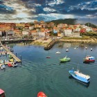 Il pittoresco porto di Finisterre, sulla Costa da Morte, accoglie pescherecci e barche da diporto in uno dei luoghi simbolo del viaggio oltre Santiago de Compostela.