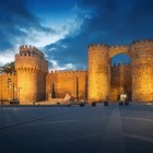 Le imponenti mura medievali di Ávila, Patrimonio UNESCO, si illuminano al calare della sera incorniciando la storica Puerta del Alcázar, simbolo della città fortificata meglio conservata di Spagna.