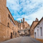 Le antiche vie del centro storico di Plasencia conducono verso la Cattedrale dell'Assunzione di Nostra Signora. Un suggestivo scorcio medievale tra edifici in pietra e silenziose strade dell'Estremadura.