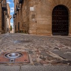 Il selciato di Calle Amargura guida lo sguardo nel centro storico di Cáceres, tra antiche facciate in pietra e un portale ad arco che custodisce l’atmosfera medievale della città.