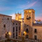 Plaza de San Jorge svela al tramonto il cuore antico di Cáceres, dominato dalla torre del Palazzo de los Golfines de Abajo, nel centro storico UNESCO dell’Estremadura spagnola.