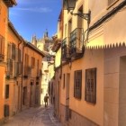 Calle Santa Isabel offre una suggestiva veduta della Cattedrale di Toledo: balconi in ferro e case dai toni caldi accompagnano lo sguardo verso la torre gotica della città.