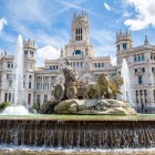 La Fuente de Cibeles domina la piazza con il carro della dea trainato dai leoni; sullo sfondo, le torri neogotiche del Palacio de Cibeles raccontano la Madrid monumentale.