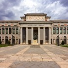 Il Museo del Prado accoglie i visitatori con il portico dorico di Juan de Villanueva: la facciata neoclassica, scandita da colonne e statue, custodisce secoli di arte europea.