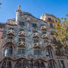 Casa Batlló sorprende su Passeig de Gràcia con la facciata ondulata di Gaudí, animata da mosaici, balconi simili a maschere e un tetto che richiama il dorso di un drago alato.