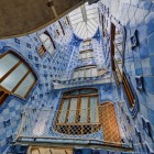 Il cavedio di Casa Batlló si sviluppa verso la luce attraverso ceramiche dalle tonalità blu graduate, finestre sinuose e balconi che riflettono il linguaggio organico di Gaudí.
