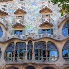 La facciata di Casa Batlló prende vita attraverso colonne dalle forme ossee, vetrate sinuose, balconi simili a maschere e mosaici colorati ispirati al mondo naturale di Gaudí.