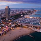 Il litorale di Barcellona si apre tra la spiaggia della Barceloneta e il Port Olímpic, riconoscibile dalle torri gemelle che segnano la trasformazione urbana avviata con i Giochi del 1992.