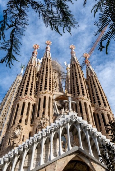 Dal basso, la facciata della Natività della Sagrada Família innalza le torri traforate di Gaudí sopra un ricco apparato scultoreo, dove architettura, natura e fede si fondono.