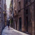 Nel labirinto del Barri Gòtic, una strada stretta segue il tracciato medievale tra portali in pietra, balconi in ferro e passaggi ombrosi, rivelando la Barcellona più antica e autentica.