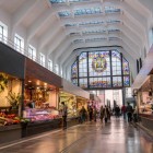 All’interno del Mercado de la Ribera, banchi di prodotti freschi animano la grande navata Art Déco, illuminata da vetrate istoriate e scandita da luminose strutture bianche.