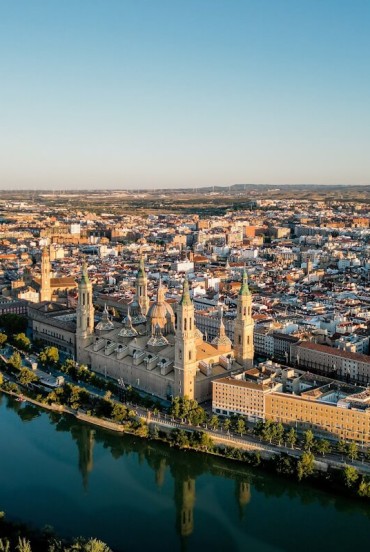 Vista aerea di Saragozza lungo l’Ebro: la Basilica del Pilar domina il centro storico con torri e cupole, simbolo monumentale e spirituale della città aragonese.