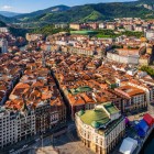 Dall’alto, il Casco Viejo di Bilbao rivela vicoli, tetti rossi e palazzi storici raccolti lungo la Ría, con il Mercado de la Ribera affacciato sull’antico cuore urbano.