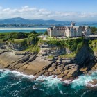 Il Palacio de la Magdalena domina la scogliera di Santander, tra pareti rocciose modellate dal mare, pinete e acque cantabriche, con la costa montuosa sullo sfond