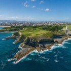 Vista aerea di Cabo Mayor, dove il faro domina le scogliere scolpite dal Mar Cantabrico, tra prati verdi e insenature, con la città di Santander sullo sfondo.
