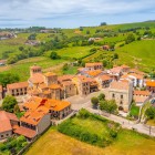 Dall’alto, Santillana del Mar rivela il borgo nato attorno alla Collegiata: tetti in cotto, torri medievali e palazzi dei secoli XIV-XVIII nel verde della Cantabria.