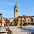 Plaza de la Constitución, cuore di Comillas, invita a passeggiare tra case cantabriche e terrazze, sotto la torre in pietra della storica chiesa di San Cristóbal.