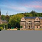 Il Palazzo di Sobrellano domina i giardini di Comillas con facciate neogotiche, logge scolpite e torri laterali, affiancato dalla slanciata Cappella-Pantheon dei marchesi.