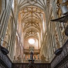 Nel coro della Cattedrale di Astorga, stalli lignei scolpiti e organo monumentale accompagnano lo sguardo verso le volte stellate, dove nervature e chiavi dorate esaltano lo slancio gotico.
