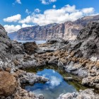 Tra rocce vulcaniche scolpite dall’oceano, una piscina naturale riflette il cielo di Tenerife, mentre le imponenti scogliere di Los Gigantes dominano l’orizzonte.