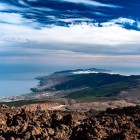 Dalle alture del Teide, lo sguardo scende dalle scure colate laviche alla verde Corona Forestal, fino ai centri abitati della costa meridionale di Tenerife e all’immensità dell’Atlantico.