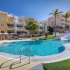 La piscina con scivolo del Servatur Isora Suites 4 stelle crea uno spazio allegro dedicato alle famiglie, tra aree verdi, palme e i luminosi edifici del resort di Puerto de Santiago.