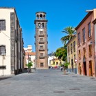 Lungo Calle Obispo Rey Redondo, storica Carrera di La Laguna, facciate coloniali e balconi canari guidano lo sguardo verso la torre in pietra della Iglesia de la Concepción.