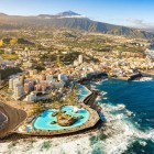 Veduta aerea di Puerto de la Cruz con il complesso balneare Lago Martiánez, progettato da César Manrique, la costa vulcanica e il Teide sullo sfondo.