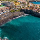 La Playa de La Arena, a Puerto de Santiago, disegna una baia di sabbia vulcanica nera bagnata da acque turchesi, tra scogliere laviche e strutture turistiche affacciate sull’Atlantico.