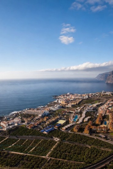Dall’alto, Puerto de Santiago si distende tra piantagioni di banani e l’oceano, mentre Los Gigantes chiude l’orizzonte con le sue imponenti pareti vulcanich