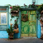 In Calle Tentenecio, una casa terrera canaria conquista con facciata turchese, infissi lignei e porta vissuta, avvolta da fiori e piante: un angolo autentico di Garachico