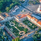 Dall’alto, il Palazzo Nazionale di Queluz appare come una raffinata residenza reale, incorniciata da giardini barocchi, parterre ornamentali, fontane e lunghe ali dai caratteristici tetti rossi.