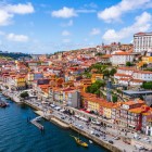La veduta aerea segue il Douro lungo la vivace Ribeira di Porto, dove facciate colorate, terrazze e antichi moli si dispongono ai piedi della collina, raccontando l’anima mercantile della città.