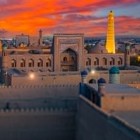 Al tramonto, la Madrasa Muhammad Rahim Khan II domina Itchan Kala, mentre il Minareto Islam Khoja illuminato svetta sull’antica Khiva.
