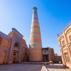 Il Minareto Islam Khodja, il più alto di Khiva, domina Itchan Kala con la sua elegante struttura affusolata, decorata da fasce di maioliche turchesi, simbolo della città storica.