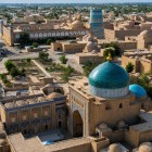 La cupola turchese del Mausoleo di Pakhlavan Mahmud domina Itchan Kala, tra madrase, minareti e mura color ocra, offrendo una suggestiva veduta sul cuore storico di Khiva.