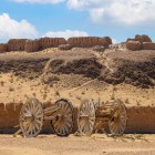 Nel deserto del Kyzylkum, le mura d’argilla di Ayaz Kala dominano l’orizzonte, mentre gli antichi carri evocano le rotte carovaniere della Via della Seta.