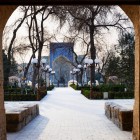 The carved wooden doors frame the path towards the Nadir Divan-Begi Madrasa, offering travellers a first glimpse of Bukhara’s tilework and historic atmosphere.