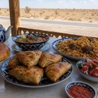 Nel cuore del Kyzylkum, un pranzo lungo la strada propone plov, samsa, shurpa, pane non e achichuk, accompagnati dall’immancabile tè verde uzbeko.Nel cuore del Kyzylkum, un pranzo lungo la strada propone plov, samsa, shurpa, pane non e achichuk, accompagnati dall’immancabile tè verde uzbeko.