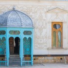 L’uscita del Palazzo Sitorai Mokhi Khosa unisce pilastri lignei turchesi, cupola metallica e stucchi floreali, raffinato incontro tra arte uzbeka e gusto europeo.