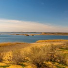 Nel deserto del Kyzylkum, il Lago Aydar sorprende con le sue acque tranquille, circondate da rive sabbiose e vegetazione spontanea: un’oasi inattesa nel cuore dell’Uzbekistan.