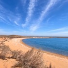 Nel deserto del Kyzylkum, il Lago Aydarkul incontra una lunga spiaggia dorata: acque celesti e dune punteggiate di arbusti creano un sorprendente paesaggio naturale.
