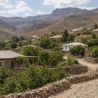 Seguendo il sentiero di Ukhum, il viaggiatore incontra case di pietra e terra, orti e alberi da frutto: una comunità raccolta tra i rilievi aridi dei Nuratau.