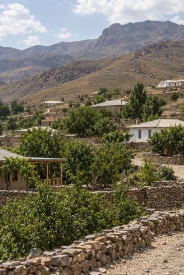 Seguendo il sentiero di Ukhum, il viaggiatore incontra case di pietra e terra, orti e alberi da frutto: una comunità raccolta tra i rilievi aridi dei Nuratau.