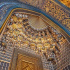 Entrando nella Madrasa Sher-Dor, lo sguardo si alza verso le elaborate muqarnas, tra motivi geometrici, iscrizioni e decorazioni dorate che rivelano la ricchezza degli interni.