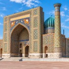 Di fronte alla Madrasa di Ulugbek sorge la seicentesca Sher-Dor, riconoscibile per il monumentale portale decorato con le celebri figure di felini e soli dal volto umano.