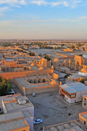Il viaggio lascia Khiva con una veduta sui quartieri storici e sulle architetture in terra cruda, introducendo il lungo trasferimento verso Bukhara attraverso il Khorezm.