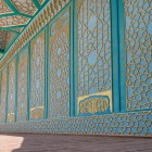 La visita prosegue sotto la veranda, dove pannelli turchesi e motivi geometrici dorati rivestono pareti e soffitto, introducendo agli ambienti interni storici del palazzo.