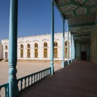 Il percorso entra nel cortile del palazzo, dove un lungo porticato dalle colonne azzurre collega gli ambienti della corte tra soffitti geometrici e facciate bianche del complesso.